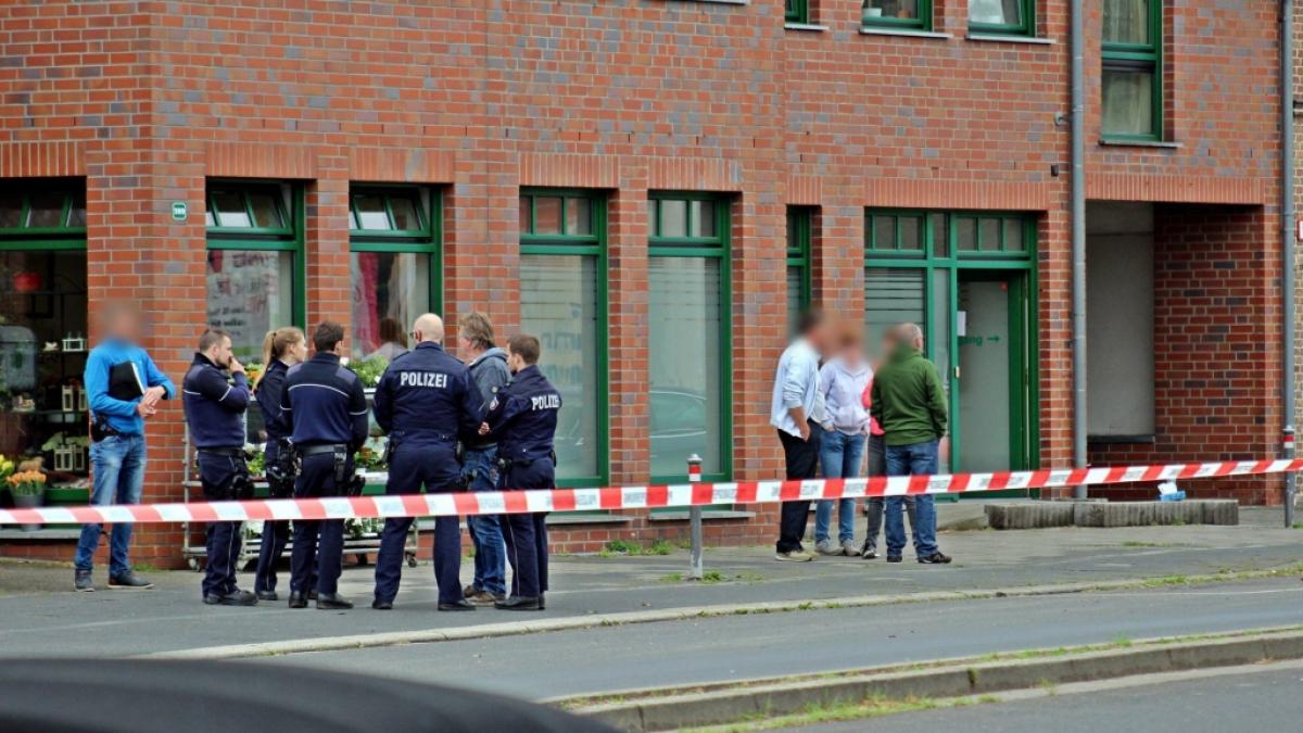Polizisten und Passanten stehen vor einem Haus in der Innenstadt von Neuss. Nach Sch&uuml;ssen ist eine 27-j&auml;hrige Frau gestorben. (Foto)