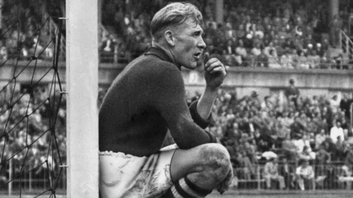 Der in Deutschland geborene, englische Torh&uuml;ter Bernd ("Bert") Trautmann von Manchester City sitzt bei einem Freundschaftsspiel gegen den FSV Frankfurt im Frankfurter Waldstadion an einem Pfosten und schaut den Aktionen im Feld zu. (Foto)