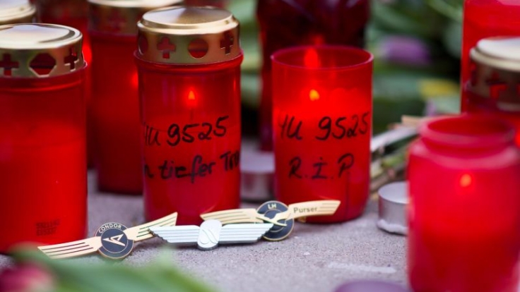 Grablichter mit der Flugnummer «4U9525» stehen vor der Zentrale von Germanwings in Köln. Davor liegen Anstecker von Condor, Air Berlin und Lufthansa.