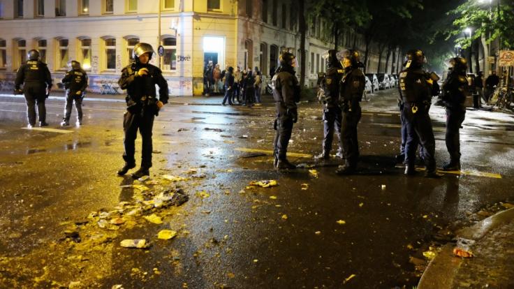 Polizisten sichern eine Straße im Osten der Stadt, im Hintergrund sind die Reste einer Barrikade zu sehen.