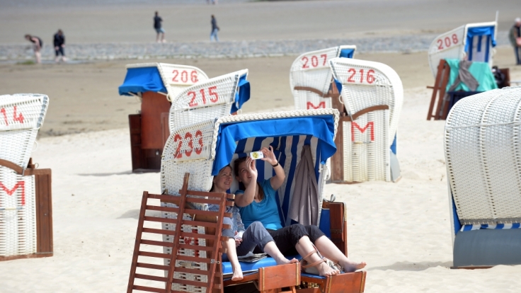 Sonnenbad am Strand. Ein Selfie darf natürlich nicht fehlen, doch landet es auf Facebook, Twitter oder Instagram, bietet es Einbrechern eine Steilvorlage.