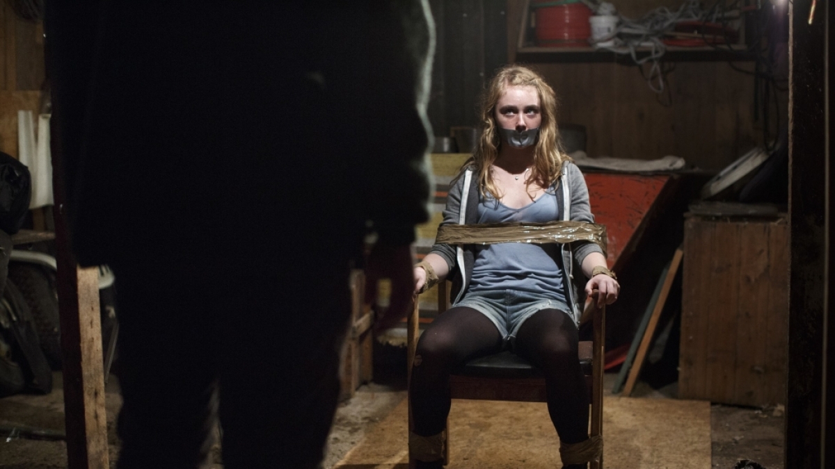 Lykke (Sara M&aring;nberg) ist mit Klebeband an einen Stuhl gefesselt und schaut einen Mann an, der ihr gegen&uuml;ber sitzt. Ihr Mund ist ebenfalls mit Klebeband beklebt. (Foto)