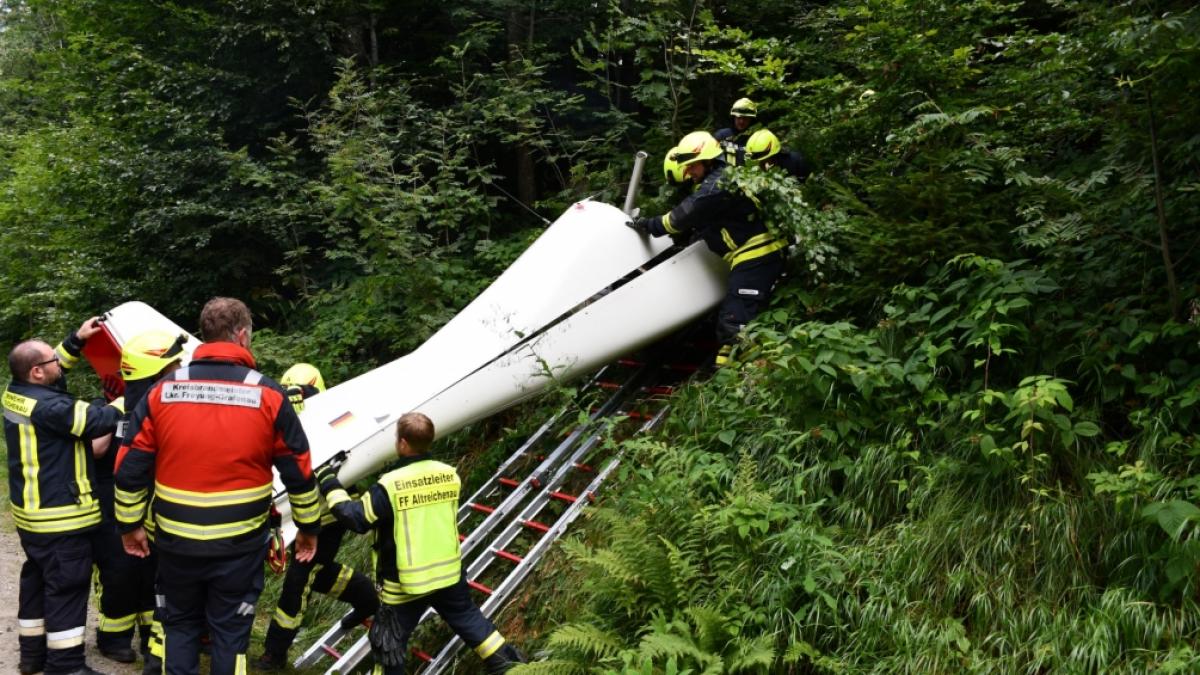 Feuerwehrleute bergen das Wrack des abgest&uuml;rzten Ultraleichtflugzeugs aus dem Dickicht eines Waldes. (Foto)