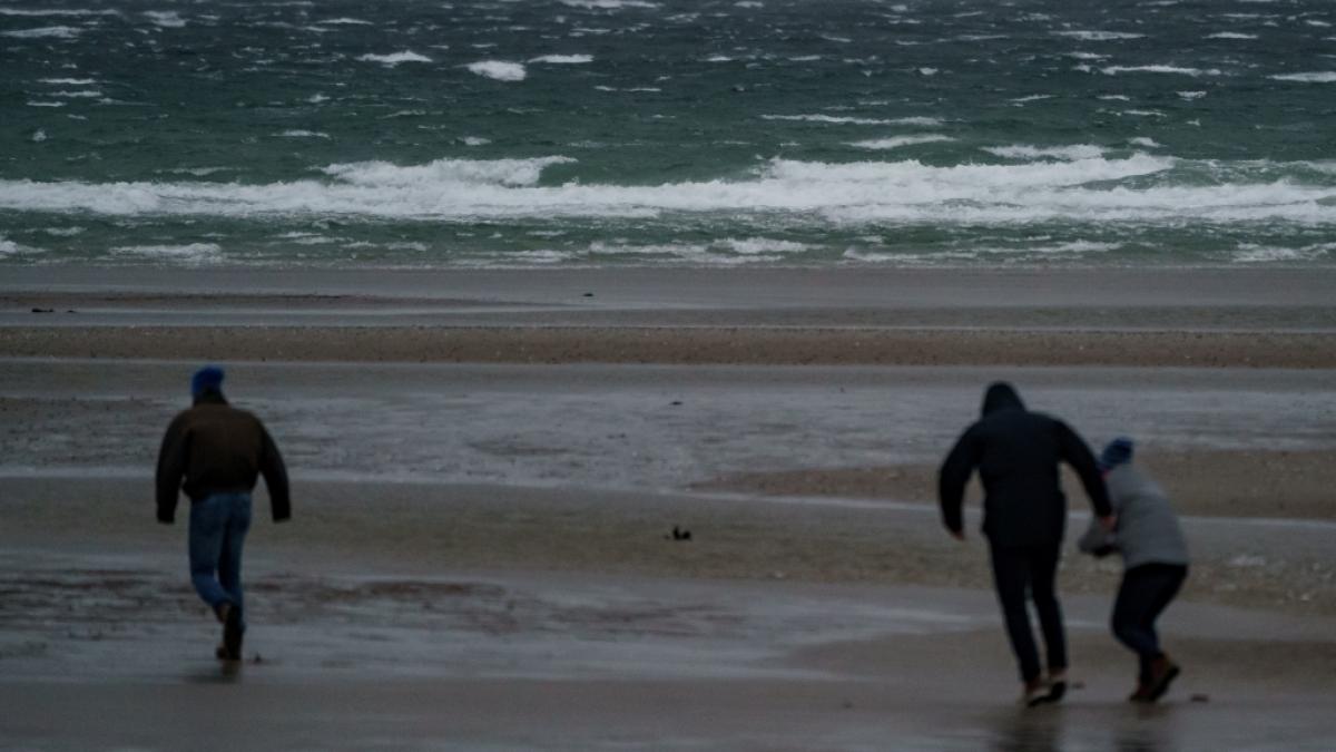 Spazierg&auml;nger stemmen sich gegen Windb&ouml;en vor dem vom Wind aufgepeitschten Wasser am Ostsee-Strand. Der Deutsche Wetterdienst DWD warnte vor Sturm am Wochenende. (Foto)
