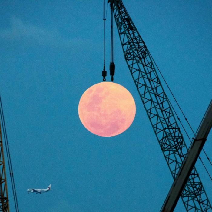 Sternschnuppen und pinkfarbener Vollmond am Himmel