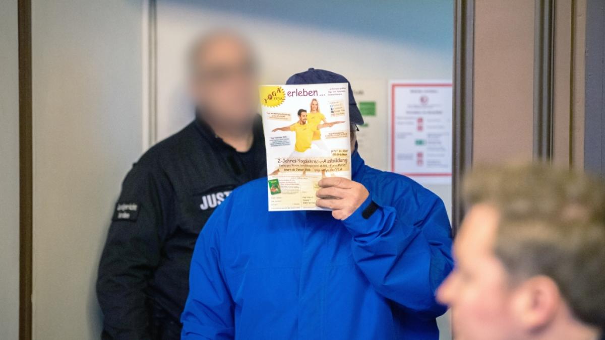 Einer der beiden Angeklagten (M) wird kurz vor Prozessbeginn von einem Justizvollzugsbeamten in den Gerichtssaal gef&uuml;hrt. (Foto)