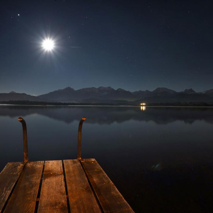 Der zunehmende Mond steht am sternenklaren Himmel über dem Hopfensee.