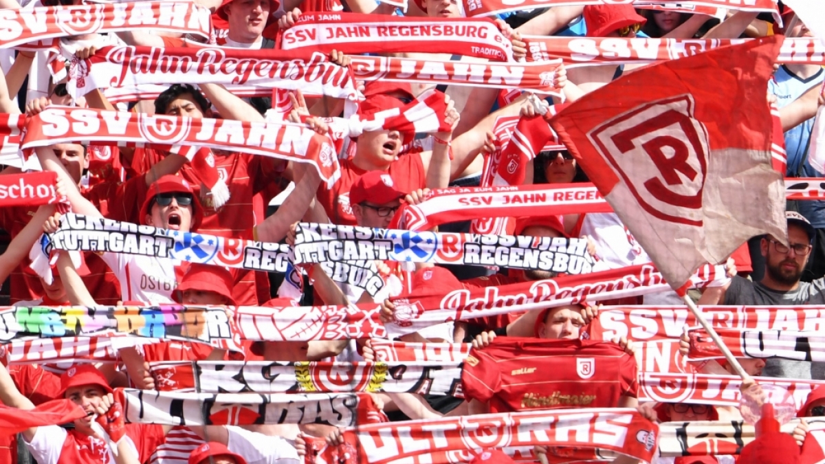 Mit ihren Schals in der Luft feuern die Fans des SSV Jahn Regensburg ihre Mannschaft an. (Symbolbild) (Foto)