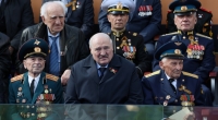 Der belarussische Präsident Alexander Lukaschenko (M) beobachtet neben Veteranen die Militärparade zum Tag des Sieges auf dem Roten Platz in Moskau.