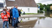 Markus Söder verschafft sich einen Überblick zur Hochwasserlage an einer überfluteten Straße nahe der Donaubrücke in Günzburg.