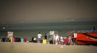 Touristen stehen an einem Strand, wohin sie wegen eines Waldbrandes auf der griechischen Insel Rhodos in Sicherheit gebracht worden sind.