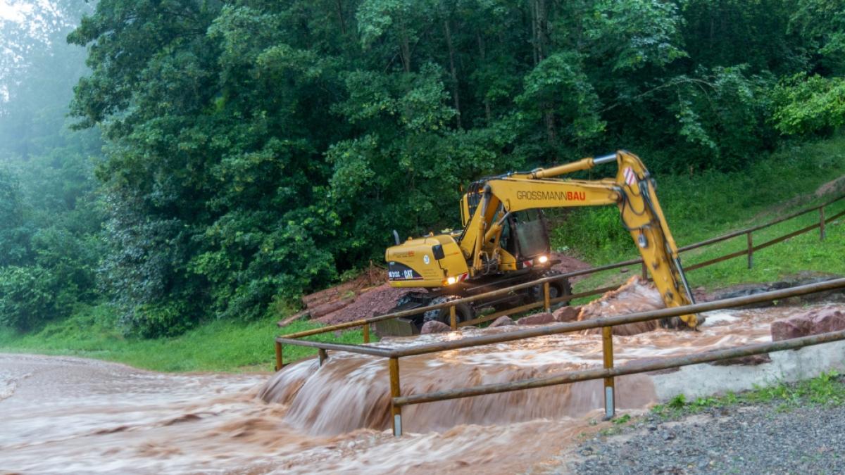 Mit schwerem Ger&auml;t arbeiten Helfer an einer &uuml;berfluteten Stra&szlig;e nach heftigen Unwettern in Altensteig. (Foto)