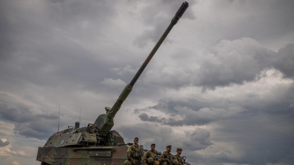 Soldaten stehen vor einem gepanzerten, selbstfahrenden Artilleriegesch&uuml;tz vom Typ Panzerhaubitze 2000 der Bundeswehr. (Foto)