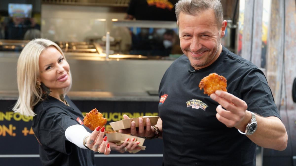 Die S&auml;ngerin Miss Sugar (l) und Reibekuchenverk&auml;ufer Willi Herren pr&auml;sentieren bei der Er&ouml;ffnung der "Willi Herren's Rievkooche Bud" die Produkte. (Foto)