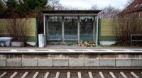 Kerzen und Blumen stehen und liegen im Bahnhof Brokstedt in einem Wartehäuschen.