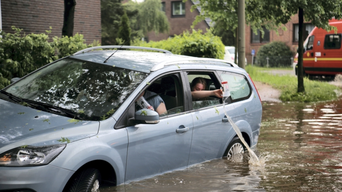Fahrzeuginsassen kippen eingelaufenes Wasser aus ihrem Auto zur&uuml;ck auf die &uuml;berflutete Stra&szlig;e in Hamburg-Bergedorf. (Foto)