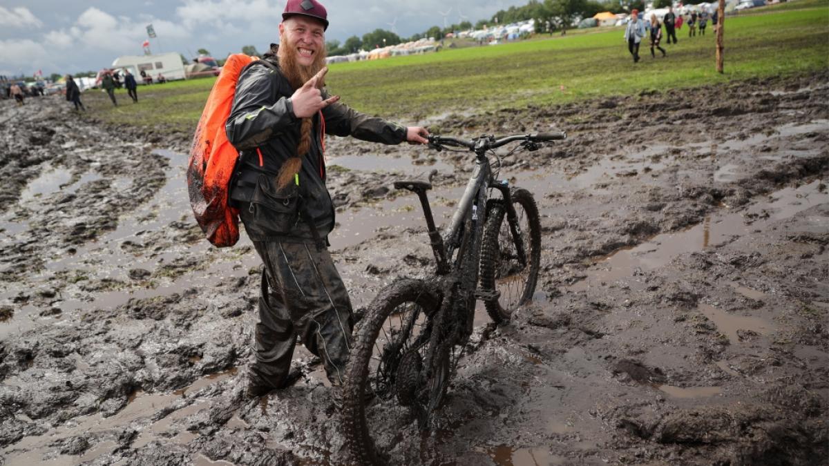 Metal-Fan Lukas Litwin aus Bochum ist mit seinem E-Mountainbike auf dem schlammigen Festivalgel&auml;nde unterwegs. (Foto)