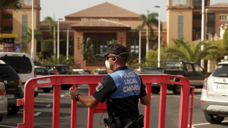 Spanien, Teneriffa: Ein Polizist setzt eine Sperre, die den Zugang zum Hotel H10 Costa Adeje Palace auf Teneriffa blockiert. Nach einem bestätigten Coronavirus-Fall ist das Hotel unter Quarantäne gestellt worden.