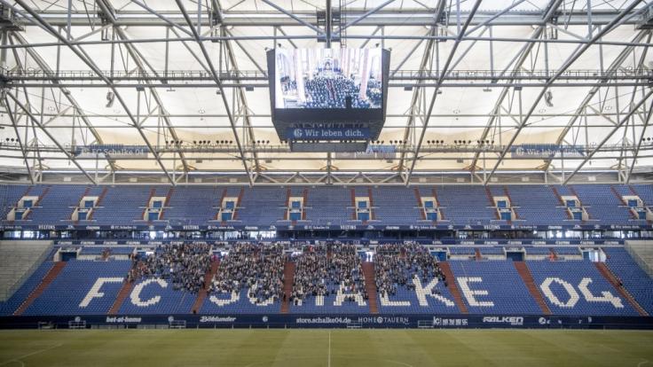 Trauernde verfolgen auf dem Videowürfel in der Veltins-ARENA die Gedenkfeier in der Propsteikirche St. Urbanus.