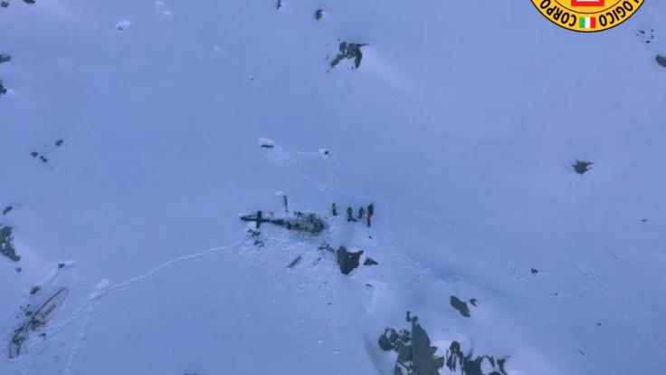 Dieses vom italienischen Bergrettungsdienst zur Verfügung gestellte Bild zeigt eine Gruppe von Bergrettern, die neben den Trümmern eines Hubschraubers stehen, nachdem dieses mit einem Flugzeug kollidiert ist.