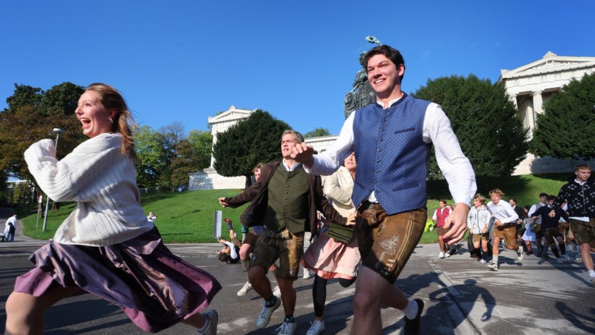 Oktoberfestbesucher st&uuml;rmen nach der Er&ouml;ffnung des Platzes, vor der Bavaria auf die Festwiese. (Foto)