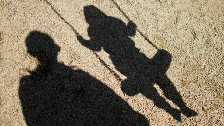 Kindermissbrauch: Schatten von einem Mann und einem Kind auf der Schaukel.