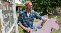 Fynn Kliemann reitet 2017 auf einem rosa Schaukelpferd über seinen Kreativhof 