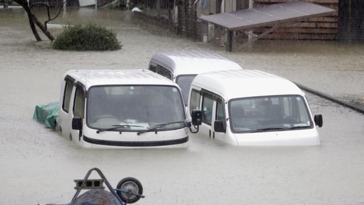 Fahrzeuge stehen in einem überfluteten Wohngebiet der Präfektur Mie.
