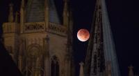 Der rötlich gefärbte Mond leuchtet am 28.09.2015 in Erfurt (Thüringen) hinter dem Dom.