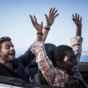 Richard (Stephan Luca, l.) zeigt Keagan (Likho Mango, r.), wie man Auto fährt.