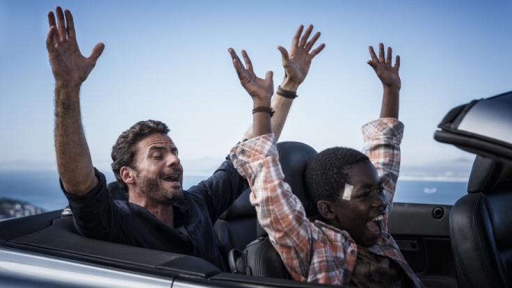 Richard (Stephan Luca, l.) zeigt Keagan (Likho Mango, r.), wie man Auto fährt.