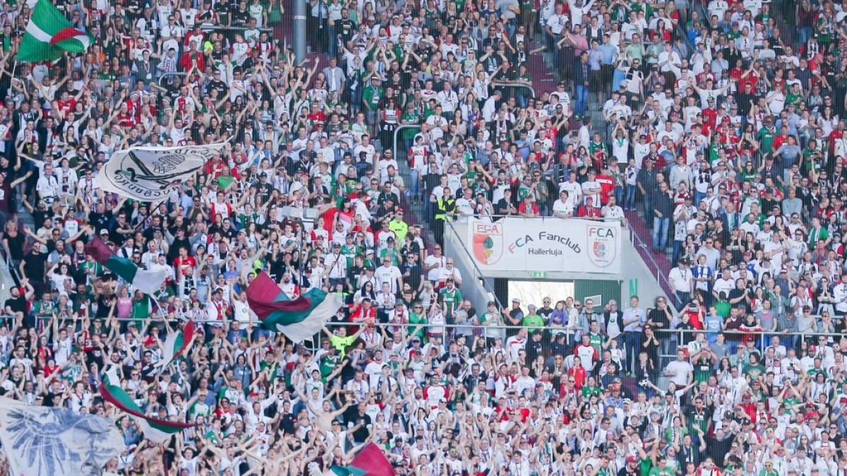 Die Fans des FC Augsburg stehen jubelnd hinter ihrer Mannschaft. (Symbolbild) (Foto)