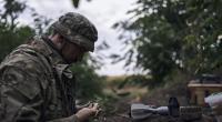 Ein ukrainischer Soldat lädt eine Bombe auf eine Drohne.