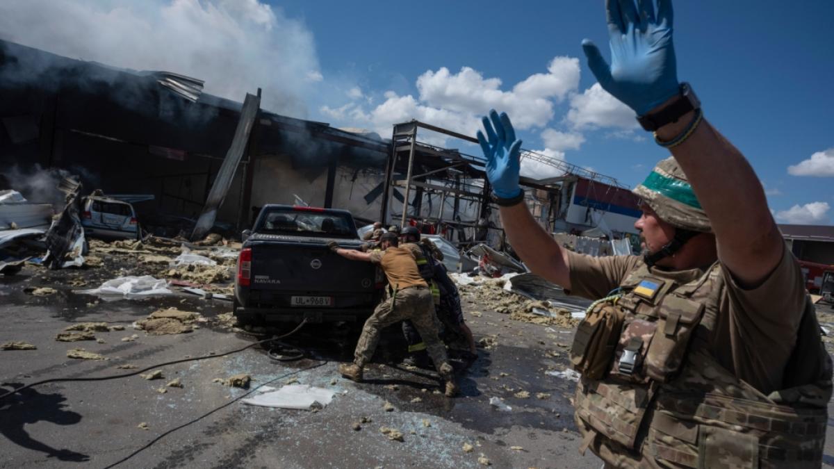 Rettungskr&auml;fte und Soldaten schieben ein besch&auml;digtes Auto, nachdem eine russische Rakete einen Supermarkt in Kostjantyniwka in der ukrainischen Region Donezk getroffen hat. (Foto)