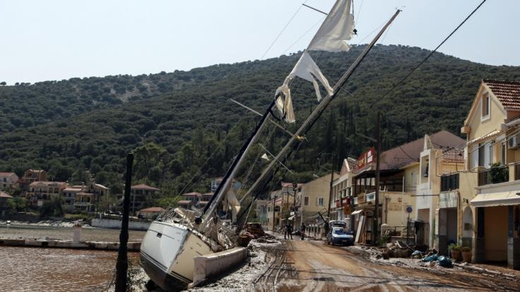 Griechenland, Kefalonia: Eine Segelyacht liegt nach einem Sturm neben einer Straße an Land.