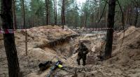 Ein ukrainischer Soldat inspiziert mit einem Metalldetektor ein Massengrab in der kürzlich zurückeroberten Stadt Isjum.