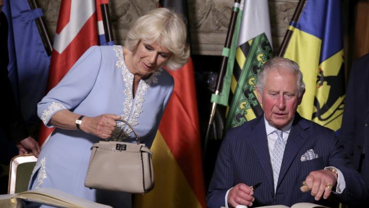 Prinz von Wales und seine Frau Herzogin Camilla tragen sich im Rathaus in das Goldene Buch der Stadt ein.