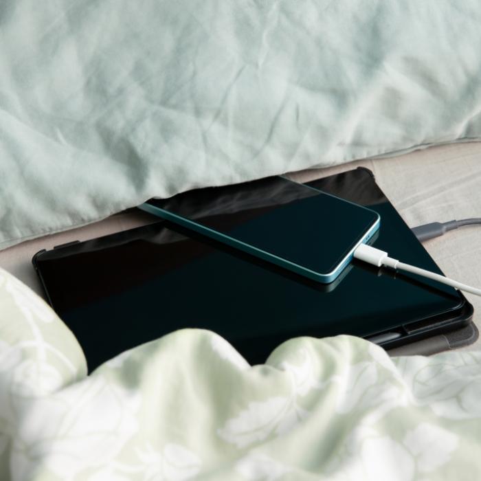 Ein Smartphone kann beim Laden im Bett schnell zur Brandgefahr werden.