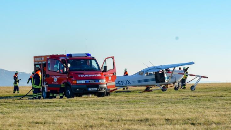 Feuerwehrleute stehen nach dem Flugunfall in Hessen neben dem verunglückten Sportflugzeug.