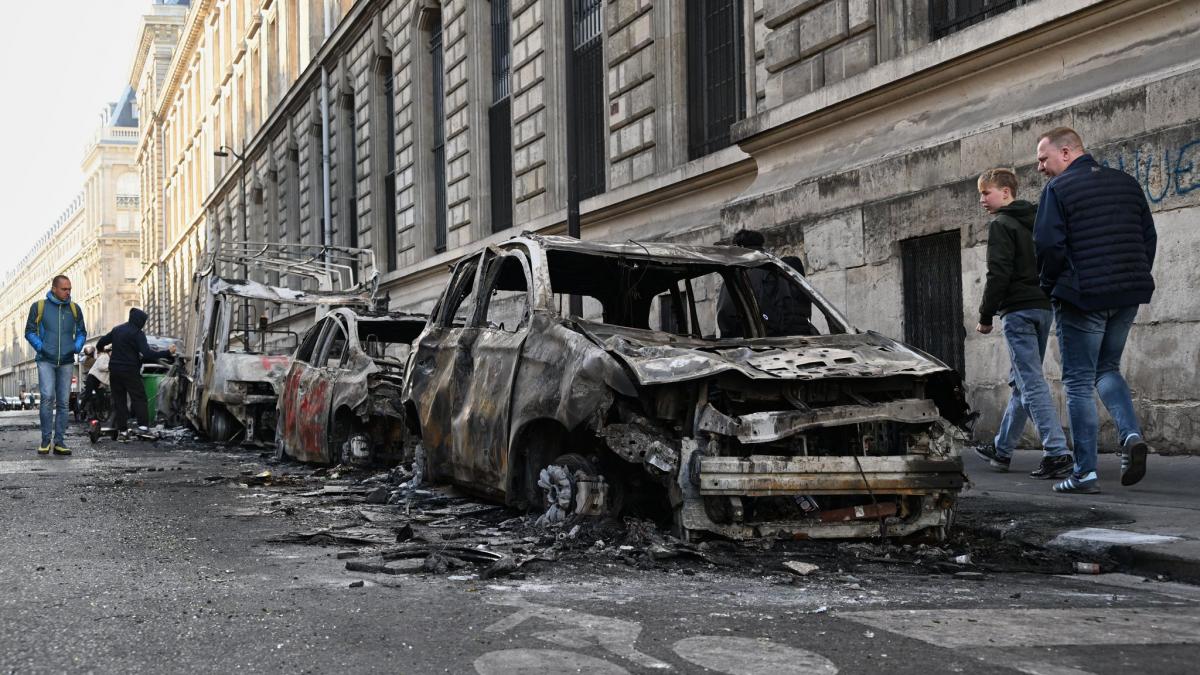 Menschen betrachten am Tag nach einer Demonstration gegen steigende Lebenshaltungskosten verkohlte Autos. (Foto)