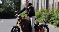 Influencer Aaron Troschke stützt sich auf ein Elektromotorrad.