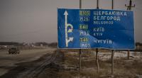 Ein Auto fährt an einem von Kugeln und Granatsplittern beschädigten Straßenschild auf der Straße zur russischen Stadt Belgorod vorbei.