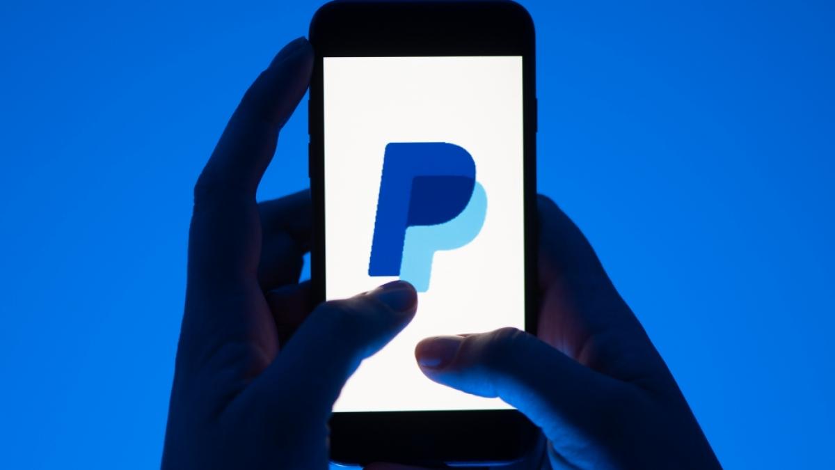 Eine Frau h&auml;lt ein Smartphone mit dem Logo des Bezahldienst Paypal. (Foto)