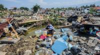 Indonesien, Palu: Agustin (51) wäscht nach dem Erdbeben Wäsche zwischen den Ruinen seines Hauses im Dorf Balaroa.