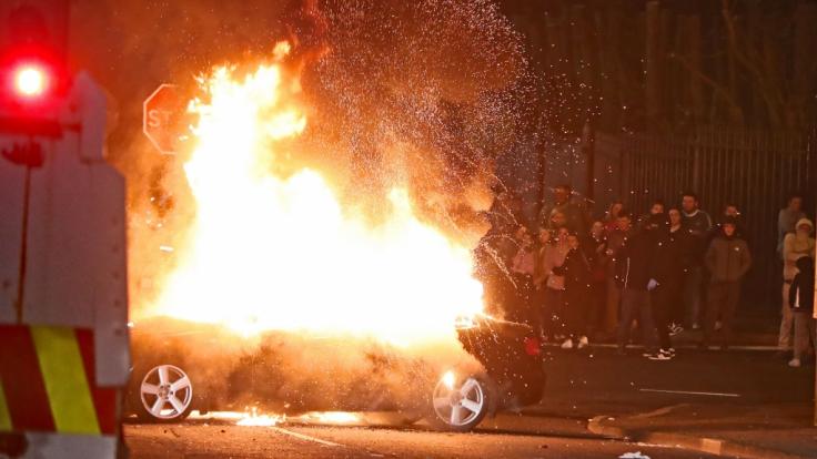 Ein entführtes Auto steht während sozialer Unruhen in Flammen.